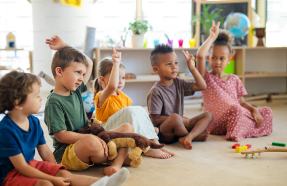 PreK students sitting on a colourful carpet engaging with their teacher.