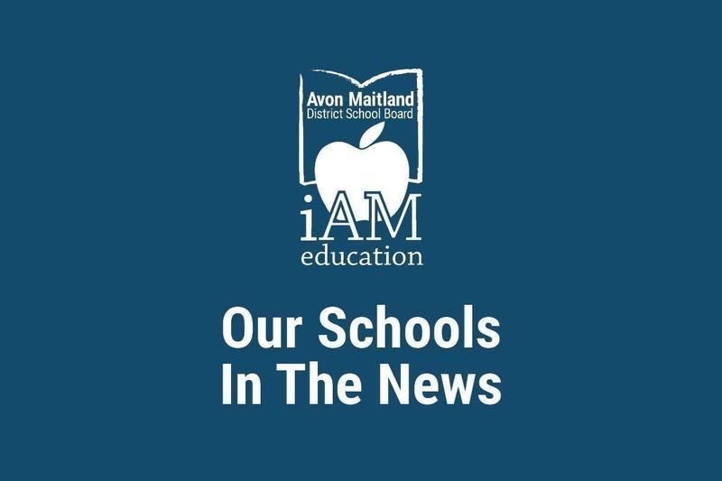 A dark blur poster with the Avon Maitland District School Board logo (an apple inside an open book) and the words “iAM education” above the headline “Our Schools In The News.”