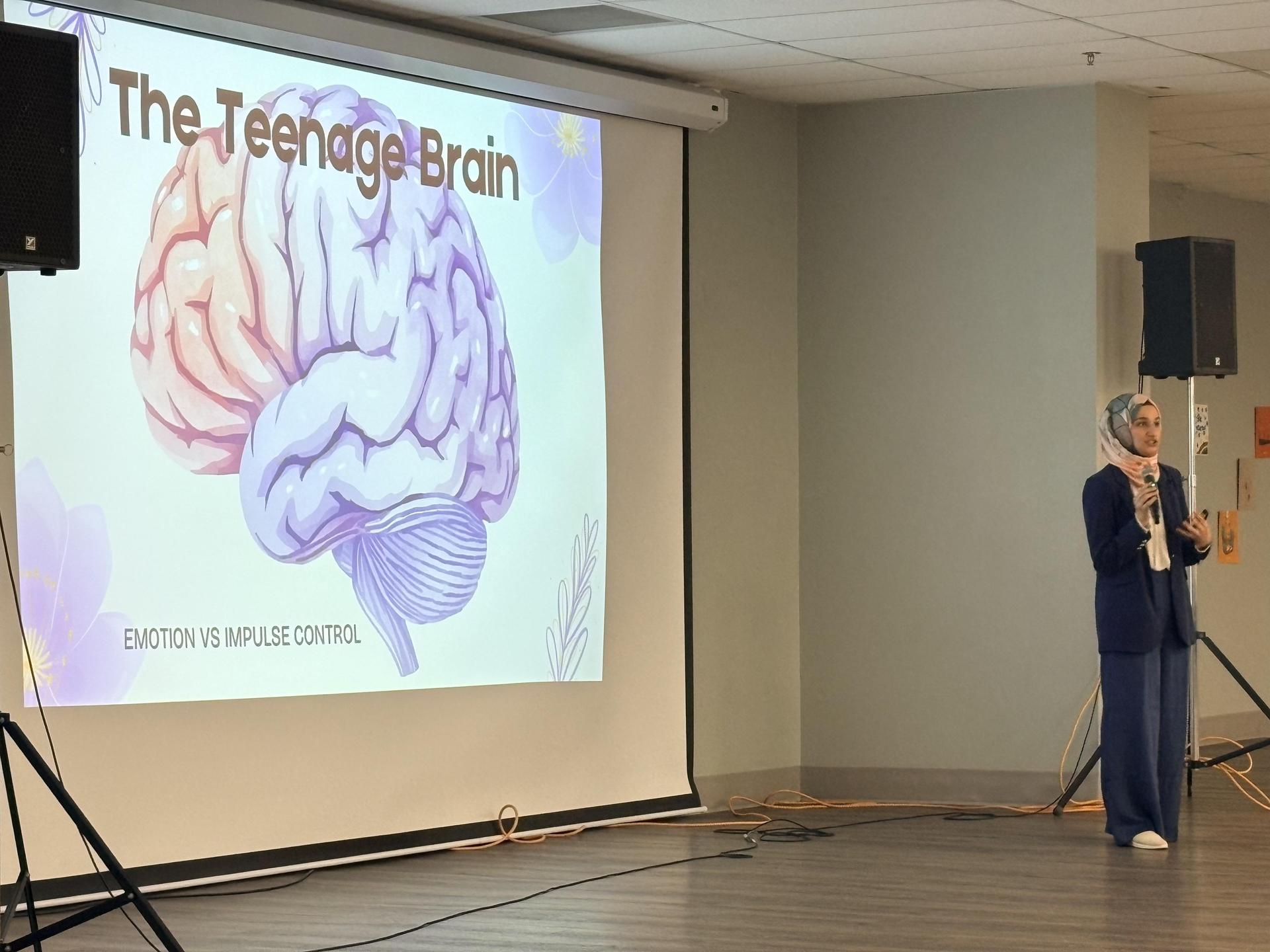 student presenting in front a slide with an image of an adolescent brain