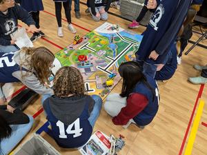 students sitting on the floor around a colourful map for lego robots