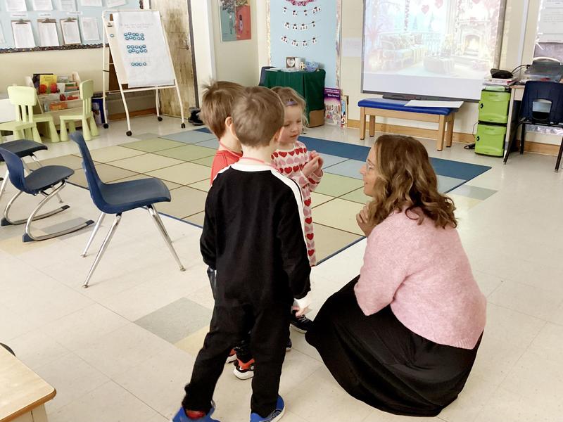 Chief executive officer kneeling down, talking to two young students