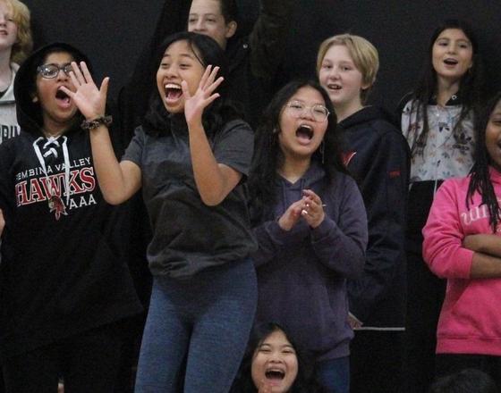 A group of diverse children joyfully singing and cheering together.