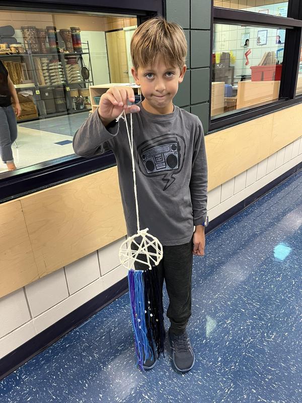 A student holding a white, blue, purple and black dreamcatcher with