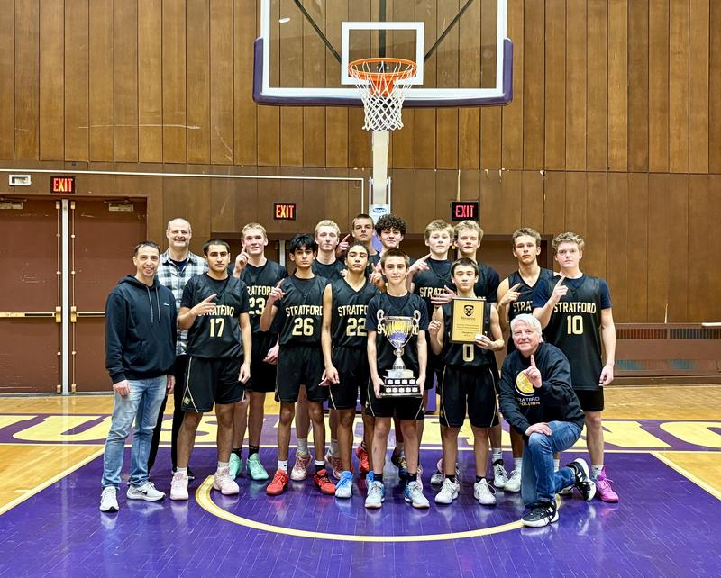 boys basketball team posing with trophy