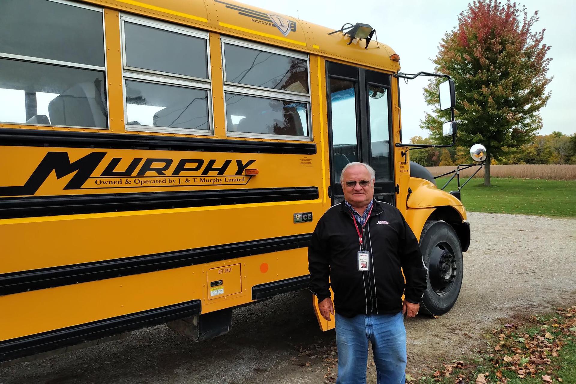  Photo of Wayne Keller standing beside a school bus