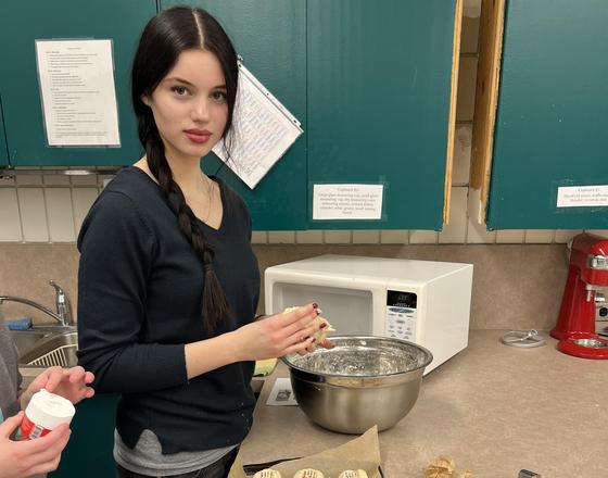 A person preparing cookies in a kitchen with a mixing bowl and ingredients.