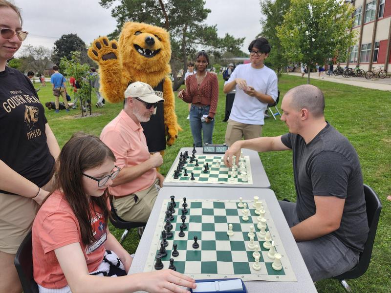 students and staff outside playing chess, golden bear mascot in back