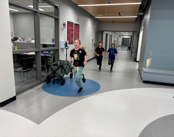 Children running down a brightly lit corridor in a school setting.
