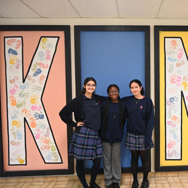 three students standing as the "i" in "kind".