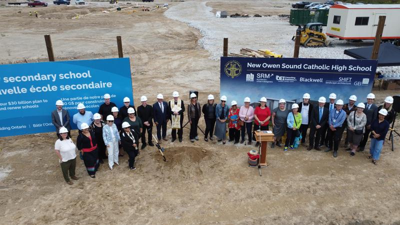 Staff and local politicians stand in front of the construction site for the groundbreaking ceremony