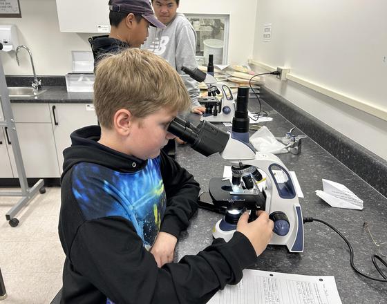 A student is looking into a microscope.
