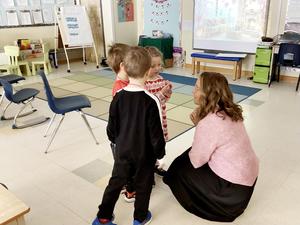 Chief executive officer kneeling down, talking to two young students