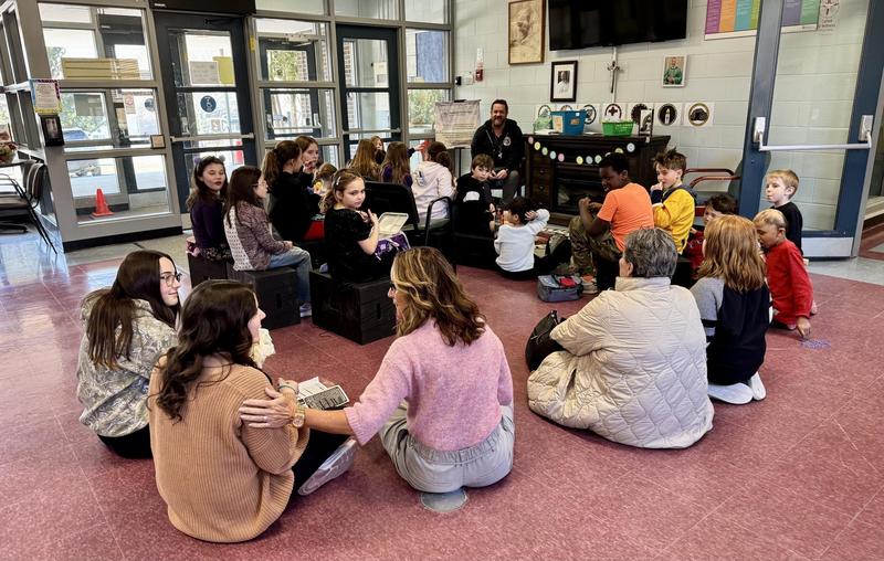 A group of students and staff sitting on the floor for a meeting