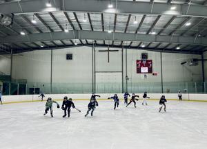 A group of students skating on an indoor hockey rink