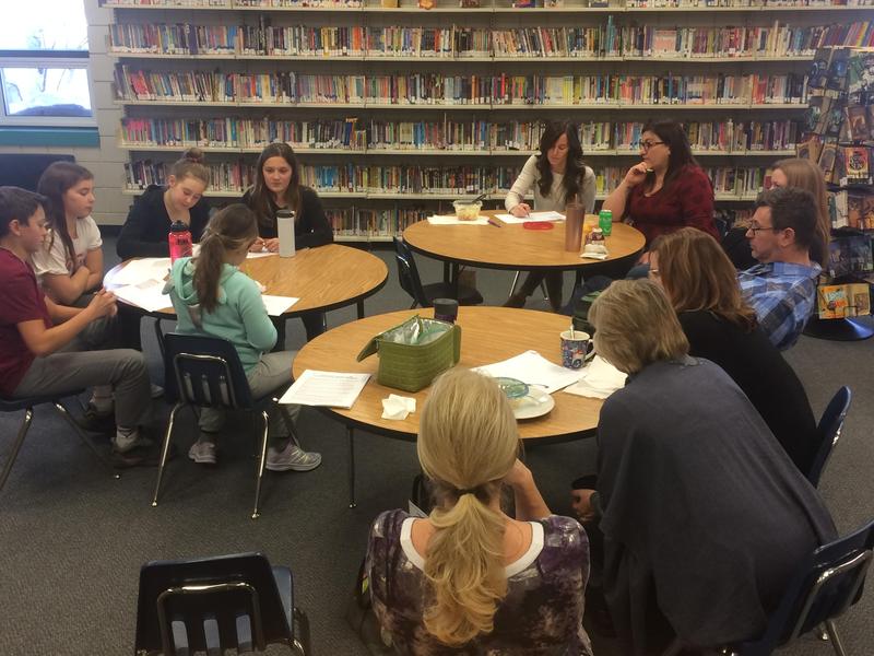 A group of people sitting at a few tables having a discussion