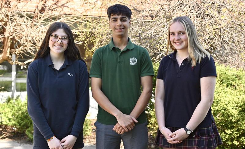 Three students standing outside, smiling