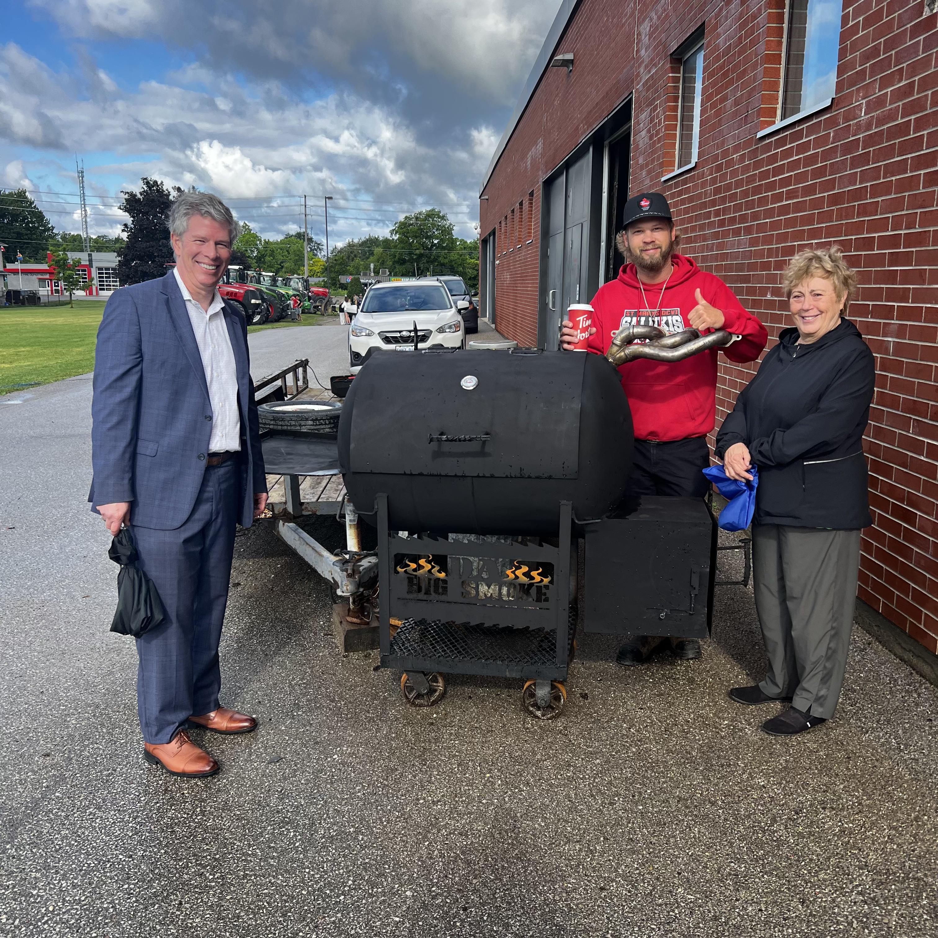 Three people standing near a bbq