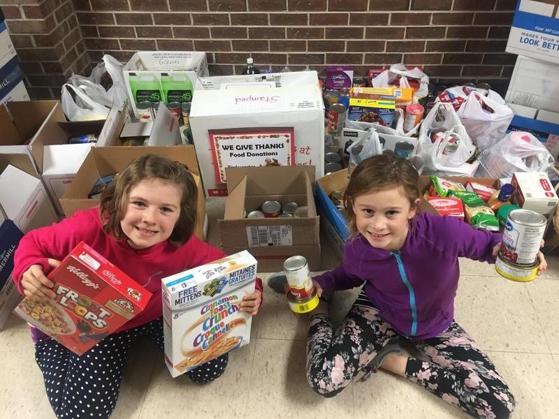 Smiling students in front of donated canned goods for