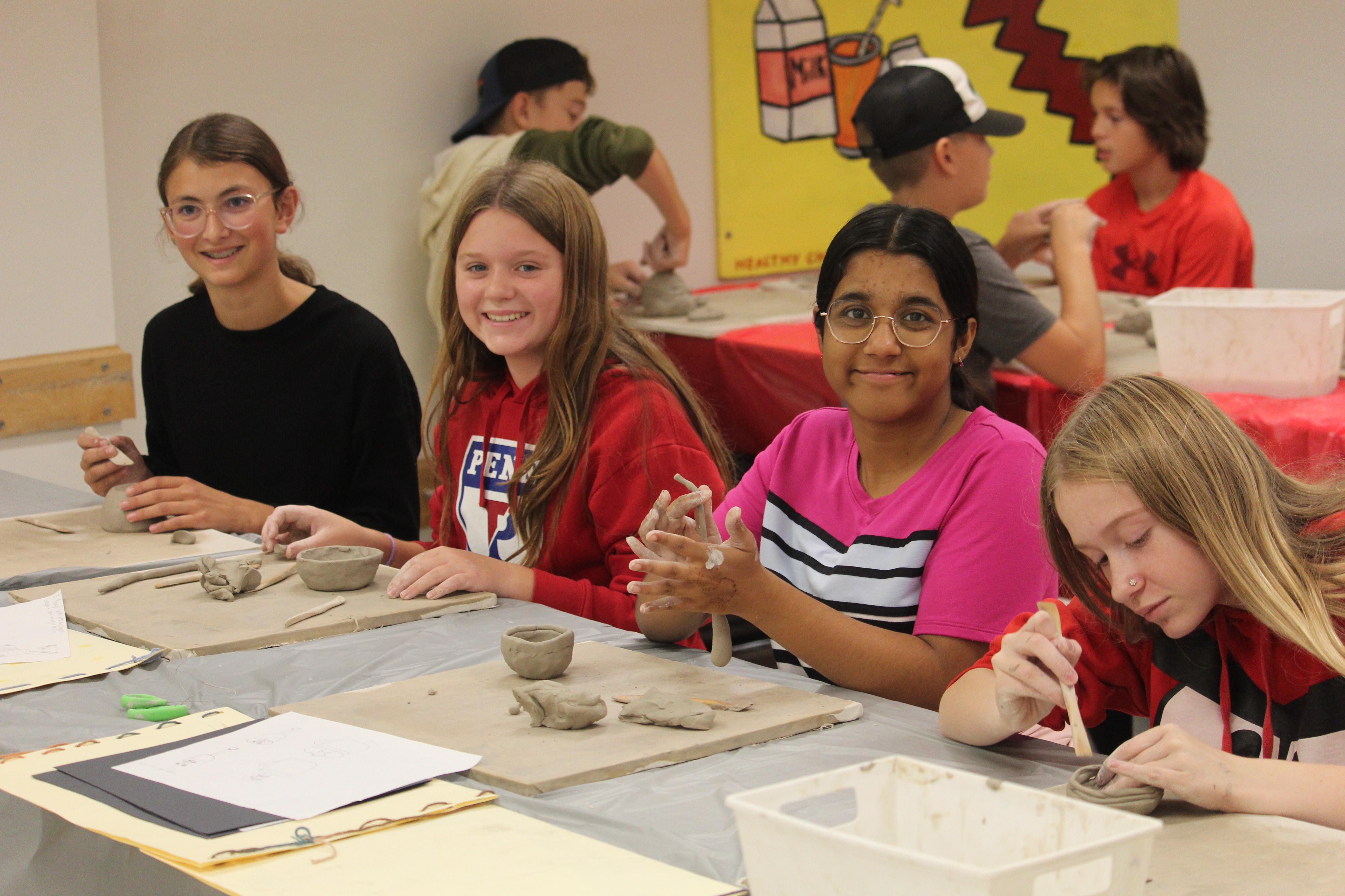 4 students work with clay in an art class.