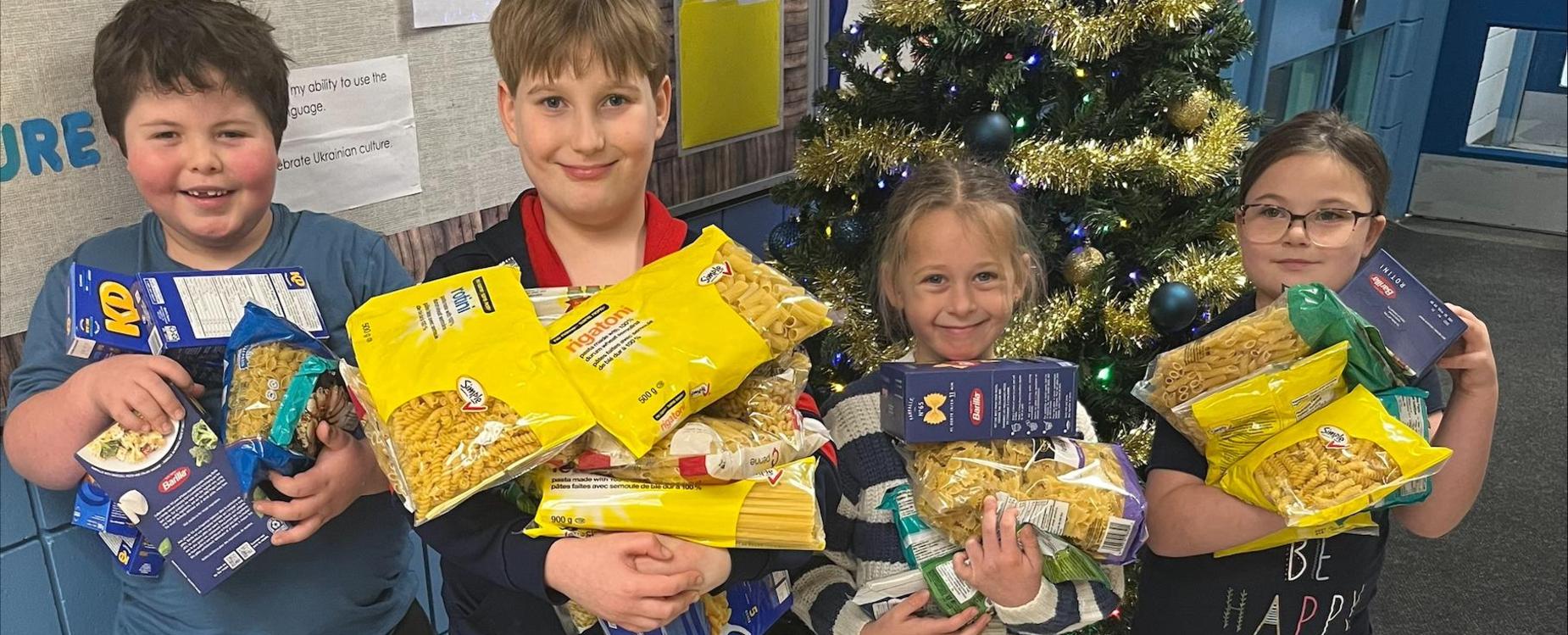 students proudly showing pasta donations for the food bank