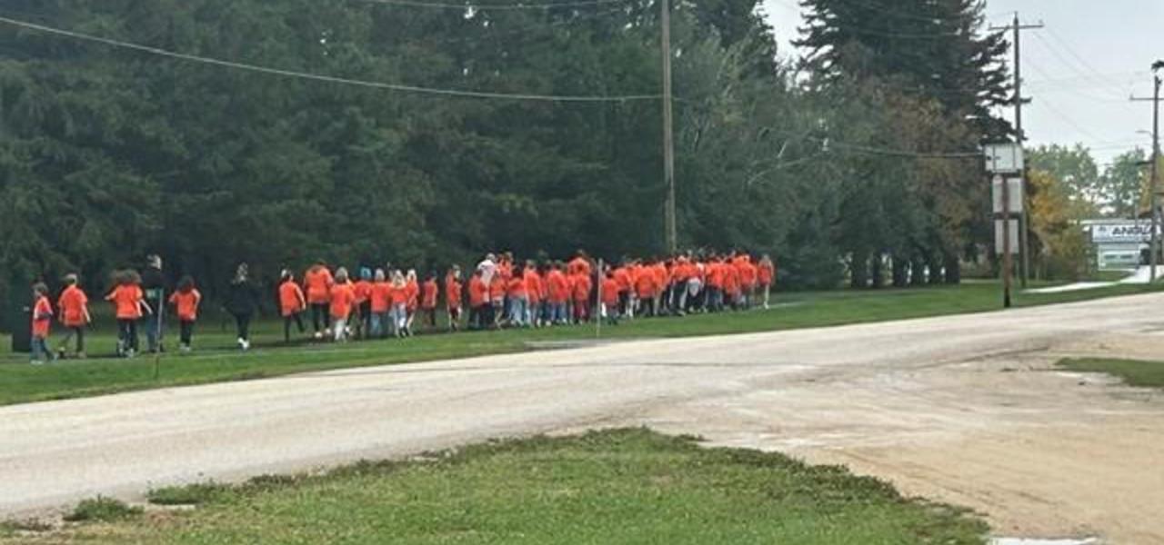 Students walking in orange shirts.