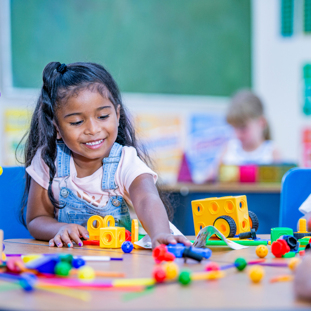 young child plays with blocks at a school desk