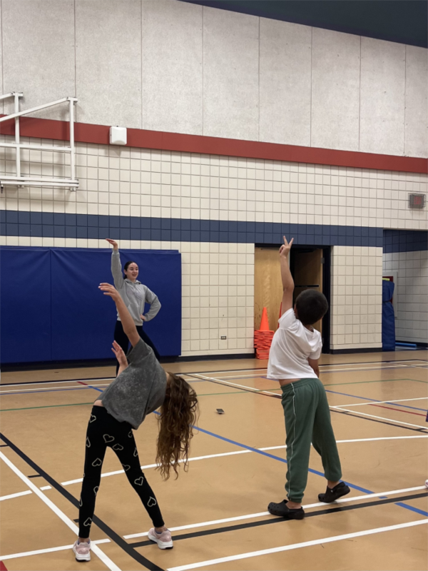 A pair of students dancing, while being led by an instructor, in the gym
