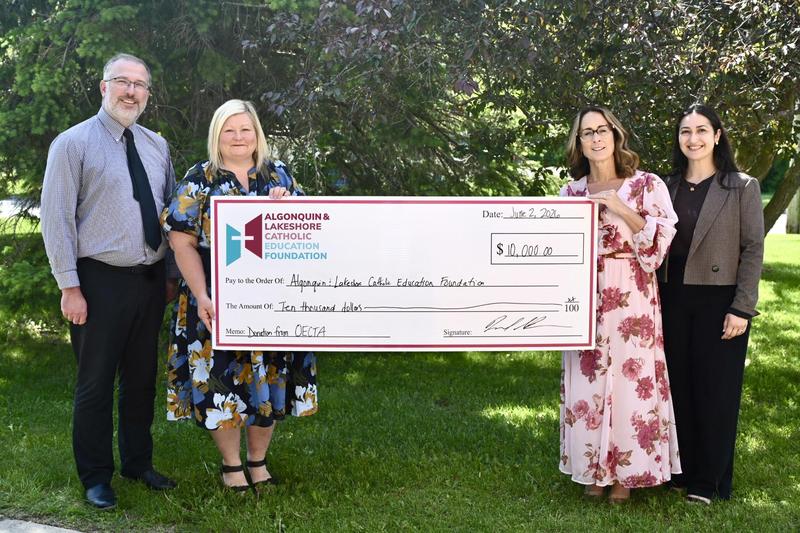 Four individuals holding a large presentation cheque.