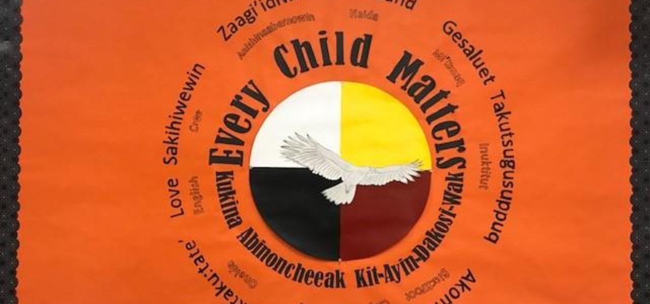 An orange poster that reads, Every Child Matters. Also written in multiple languages. Black poster surrounds the border.