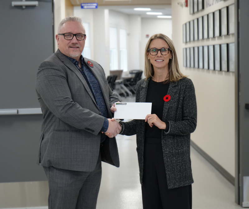 Image of a man in a suit accepting a donation from a woman in a suit.