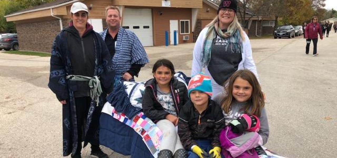 Terry Fox fundraisers on rolling cot being pushed by Mr. Plaetinck, Mrs. Bodner and Ms. Jaworski.