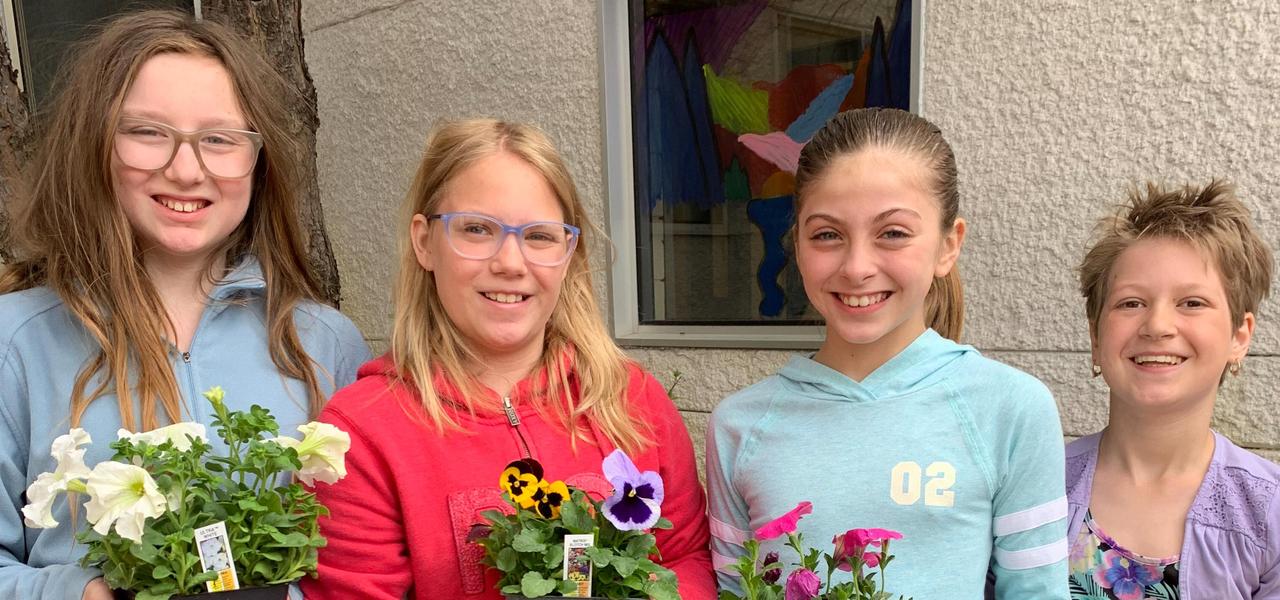 Four students holding flower pots
