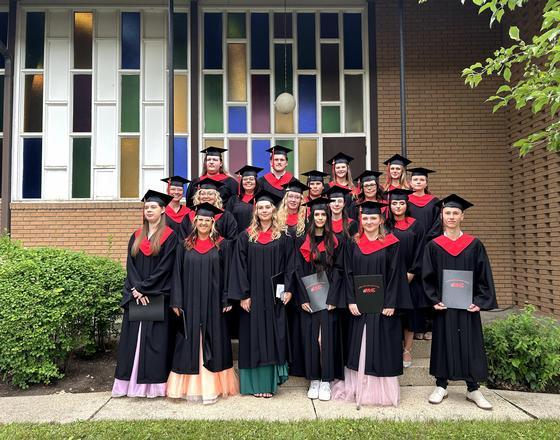 Group of graduates in caps and gowns posing outside a building.
