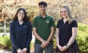 Three students standing outside, smiling