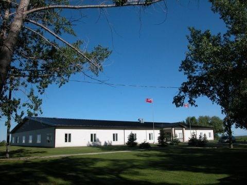 A picture of Springwell School. The building is white and roof is black. Trees are situated around the school grounds.