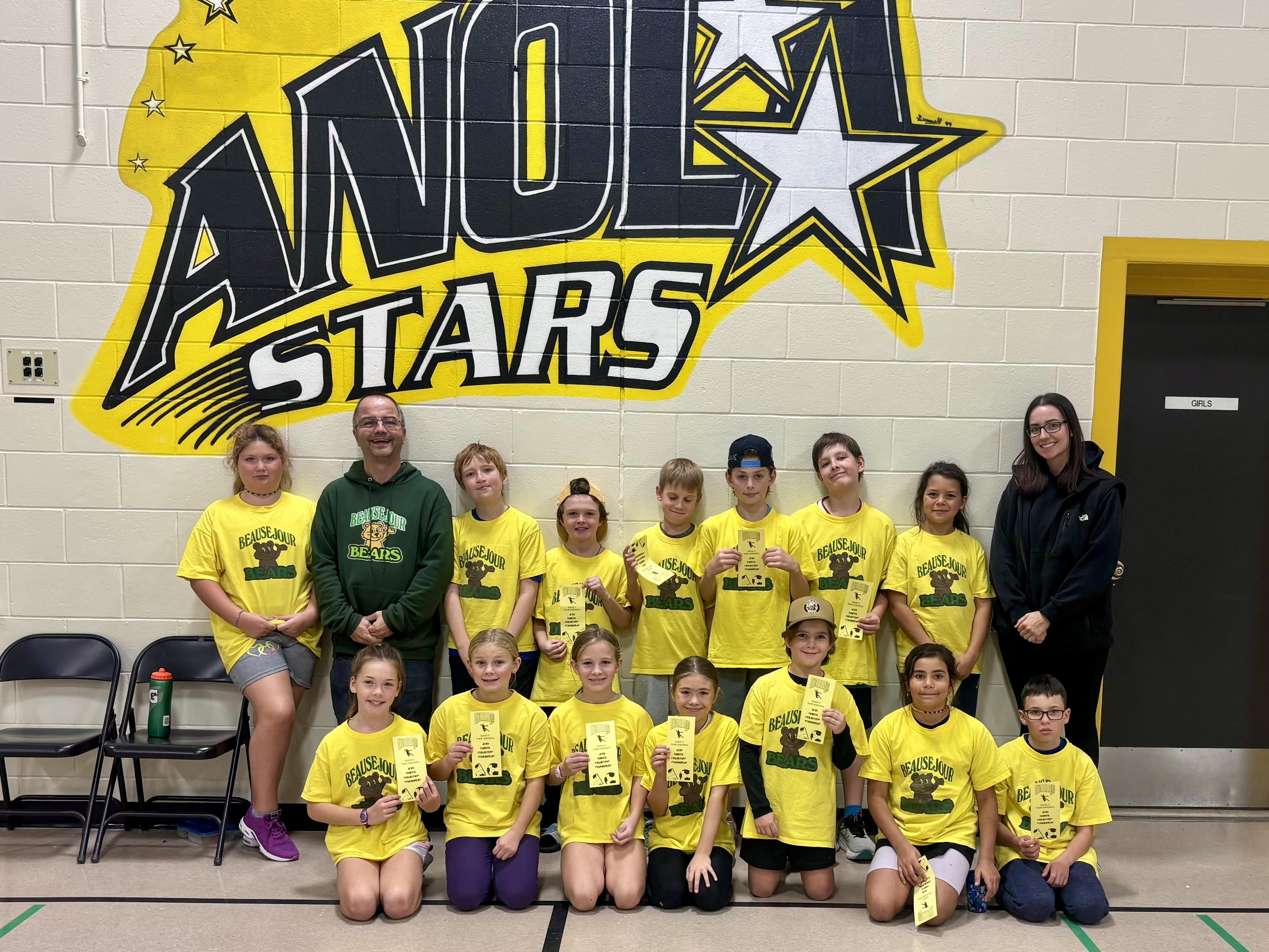 Handball students pose in front of an Anola Stars logo.