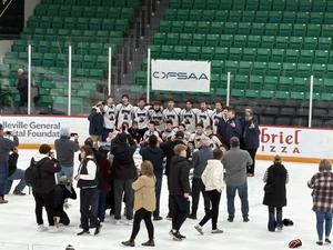 A group of secondary students on the ice, celebrating after the win of a hockey game.