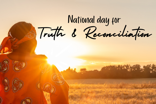 An Indigenous woman looking over a field at sunset with text