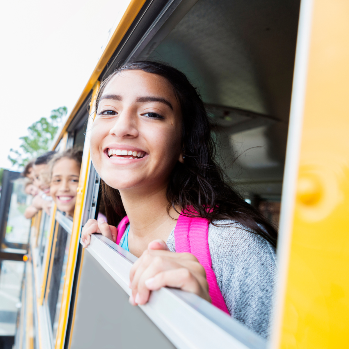 Students popping their head out a bus window.