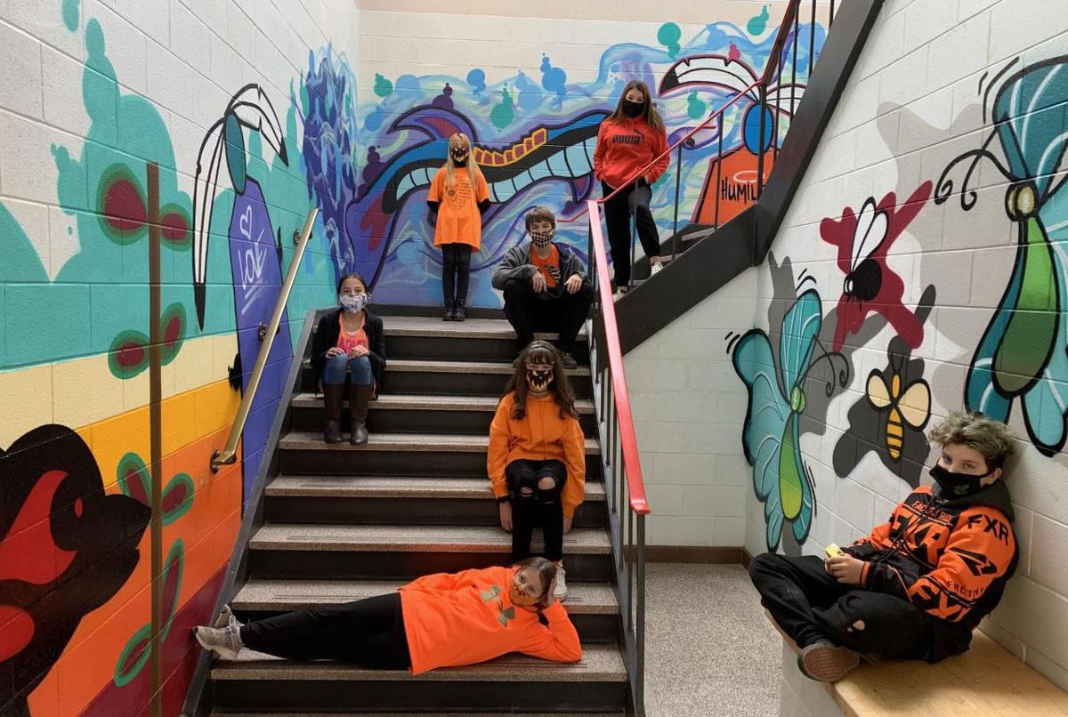 students seated in painted stairwell