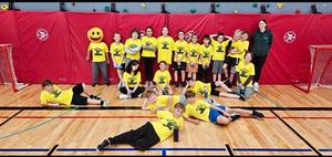 Handball students pose in front of a red gym mat