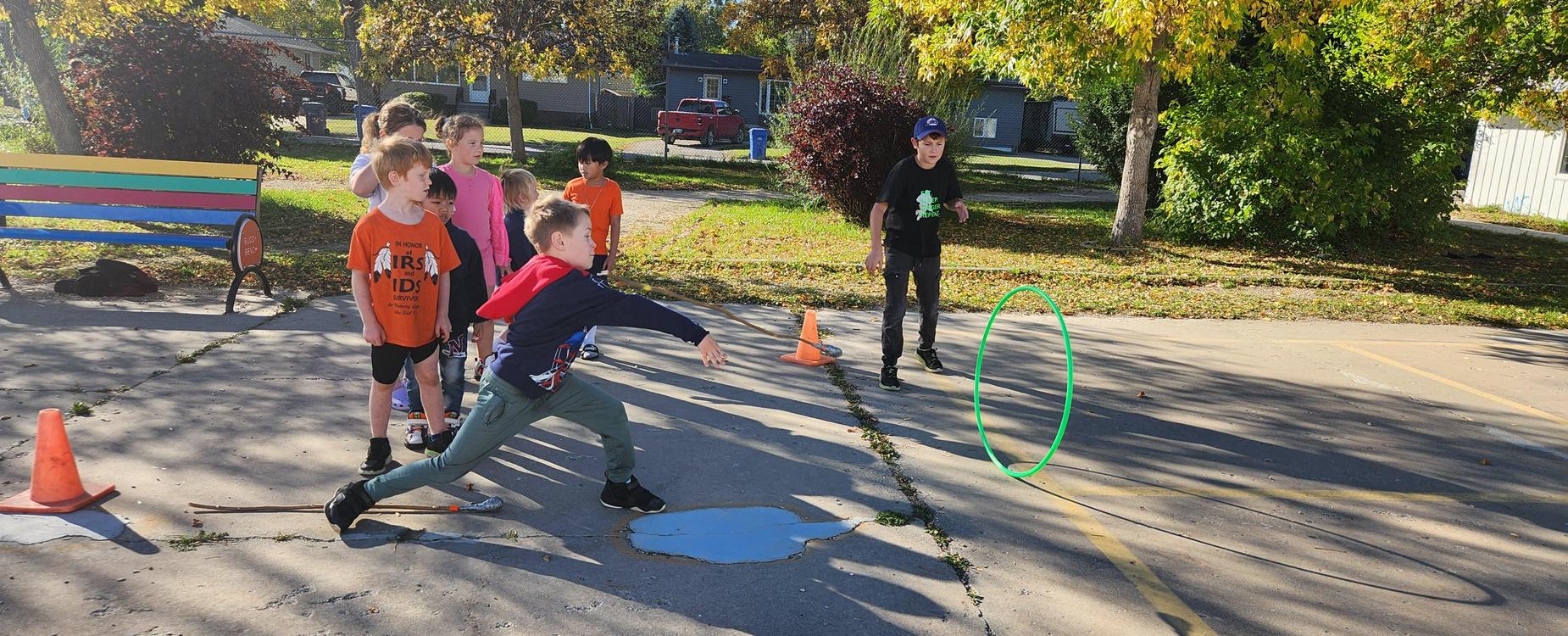 Kid playing hoop through at the schools indigenous games. He is throwing the stick through the hoop.
