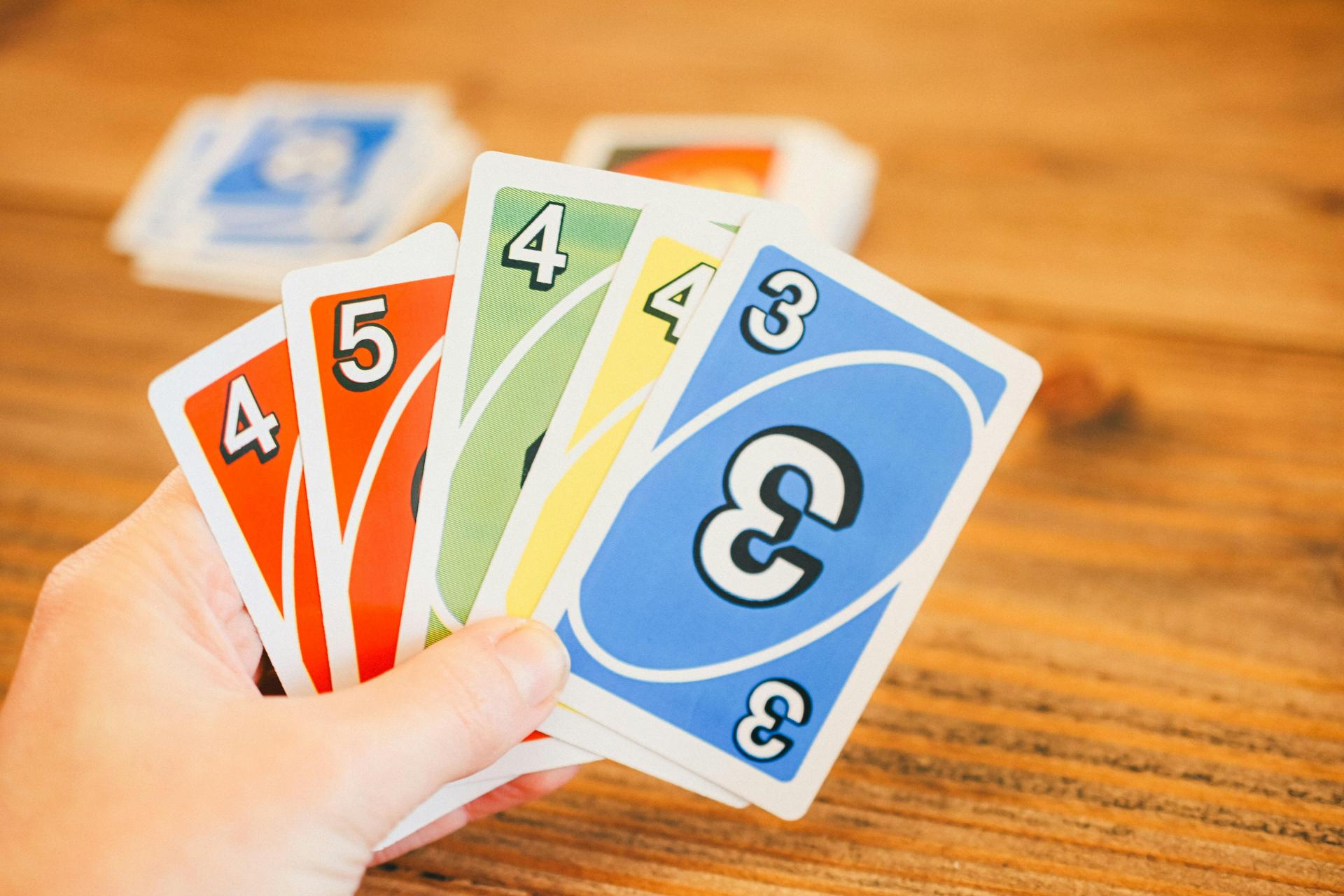 A person holding 5 uno cards