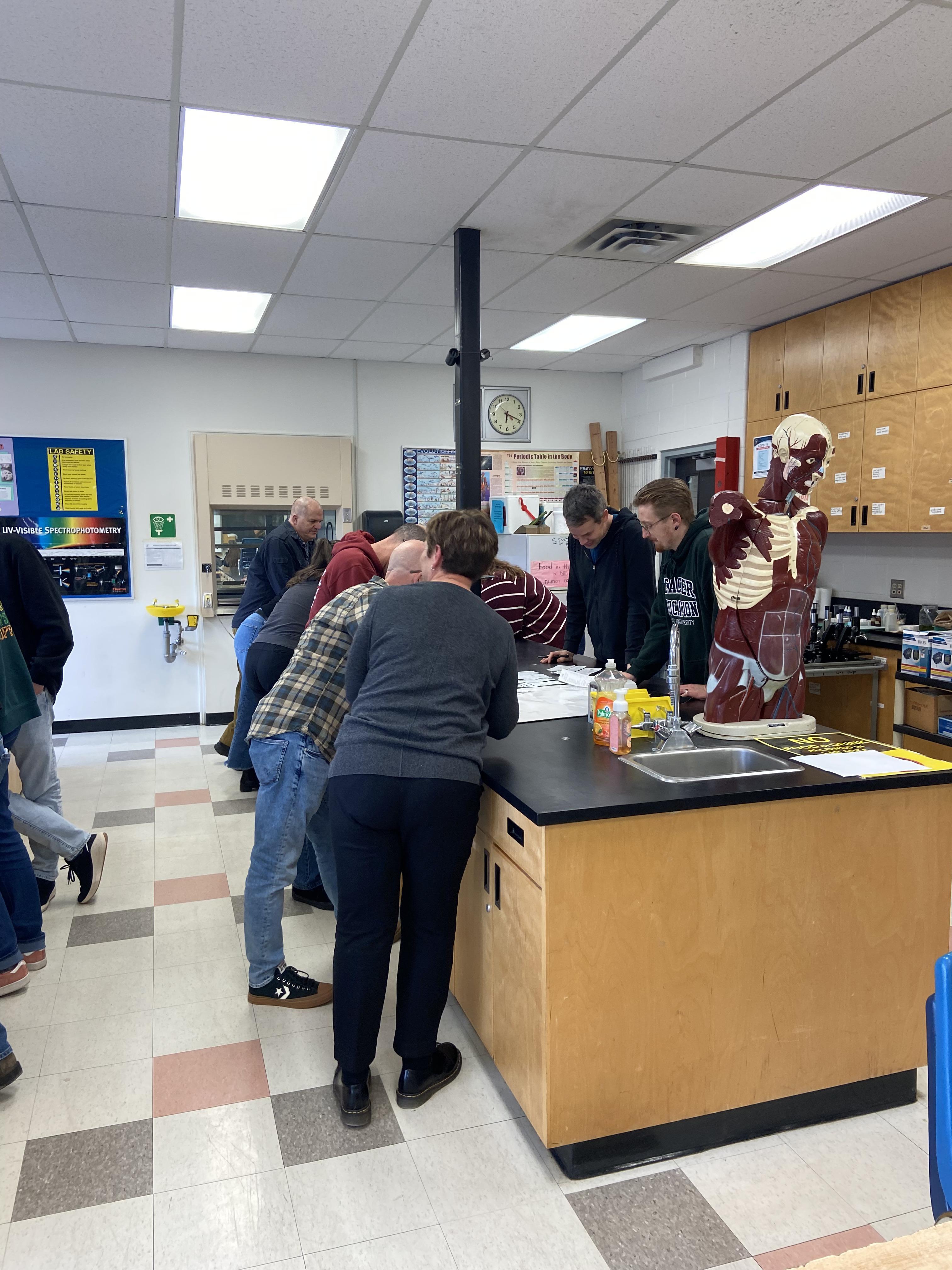 Group of people standing around an island in a classroom
